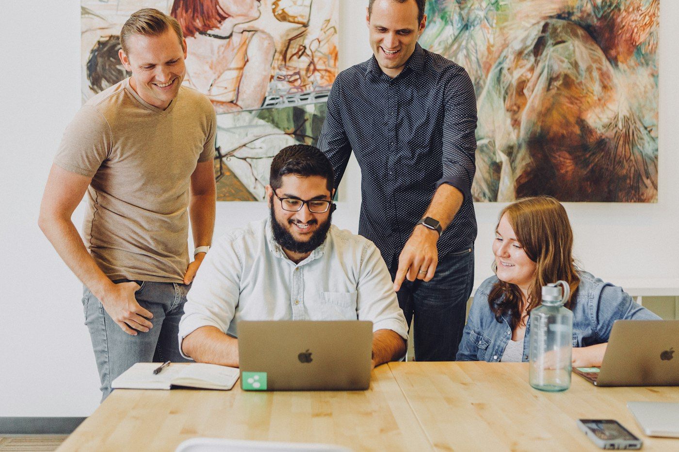 A small team laughing around a laptop